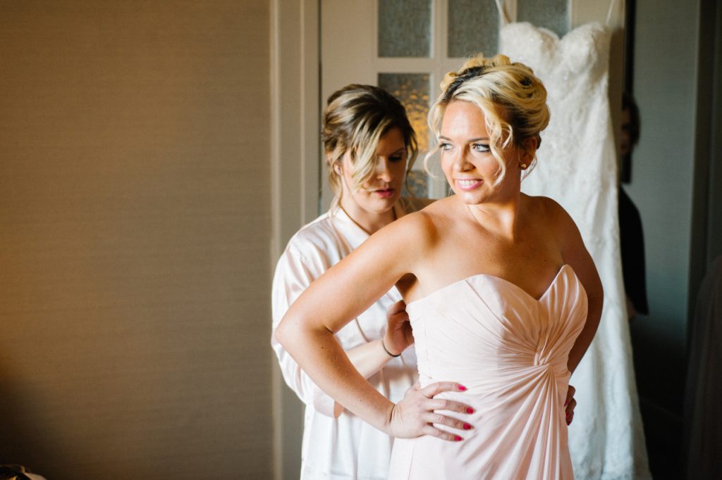 Bridesmaid getting zipped by Austyn Elizabeth Photography