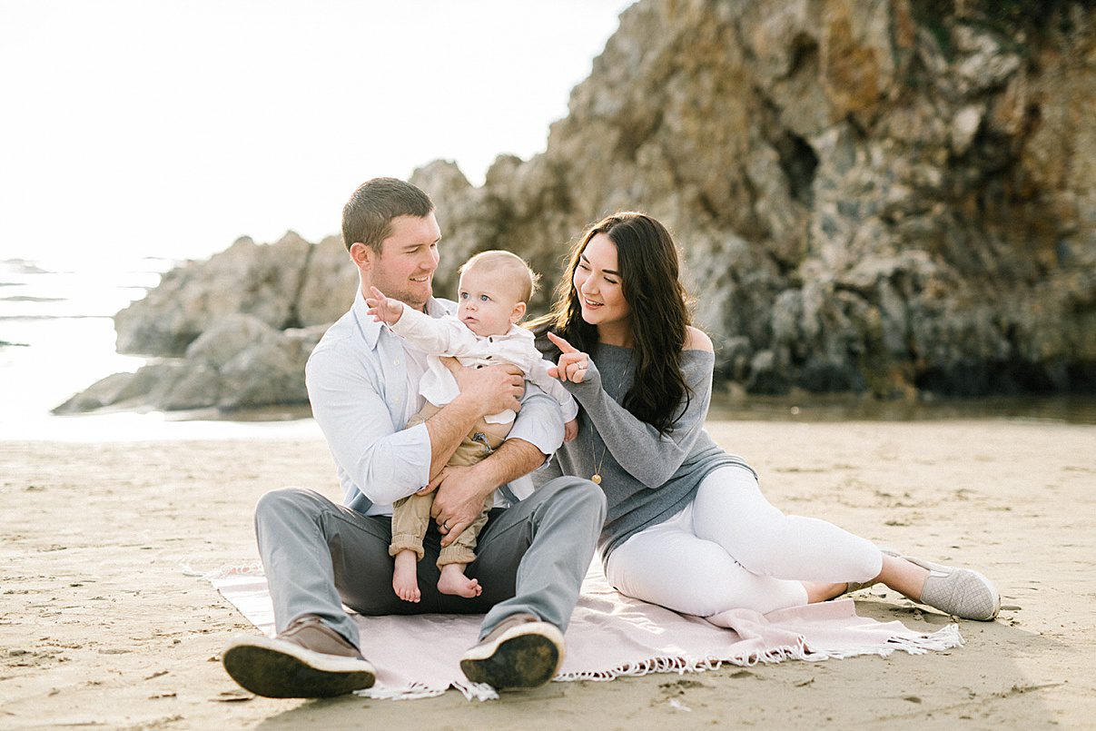 Family sitting on light pink blanket at the beach with Pismo Beach Family Photographer Austyn Elizabeth Photography