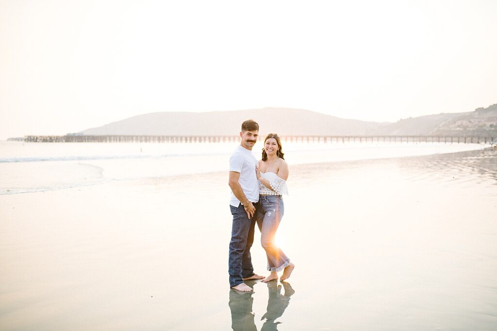 Boho couple standing in the sand at Avila Beach engagement session by Pismo Beach engagement photographer Austyn Elizabeth Photography