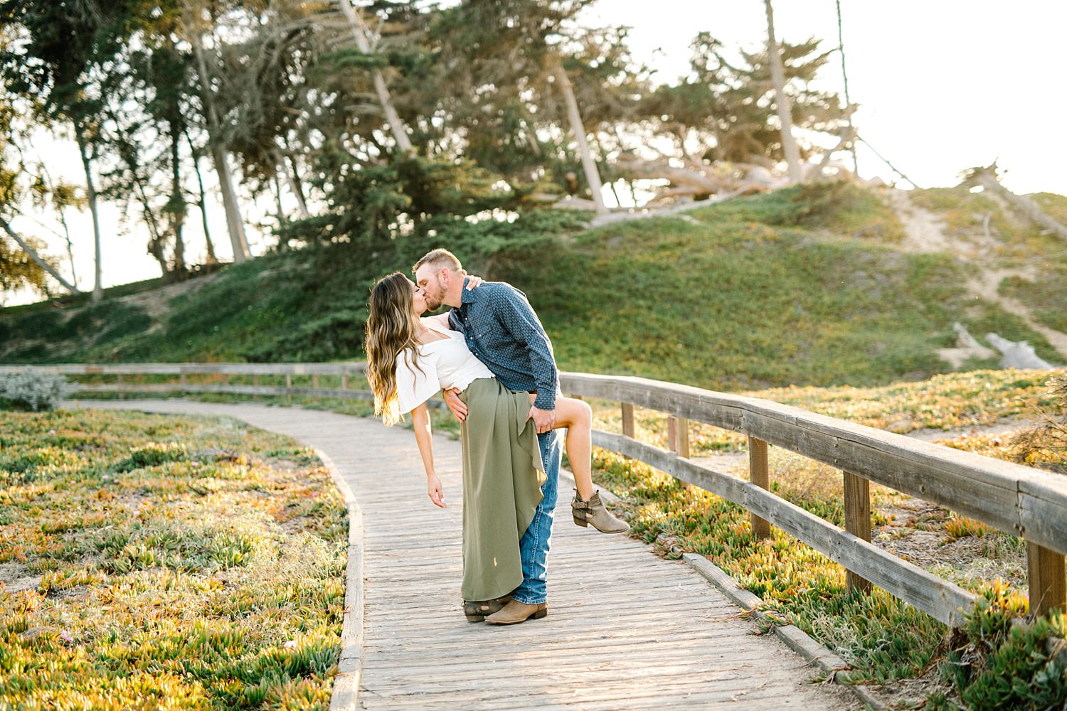 Groom dips his fiancé during beautiful sunset on Pismo Beach boardwalk by Pismo Beach engagement photographer Austyn Elizabeth Photography