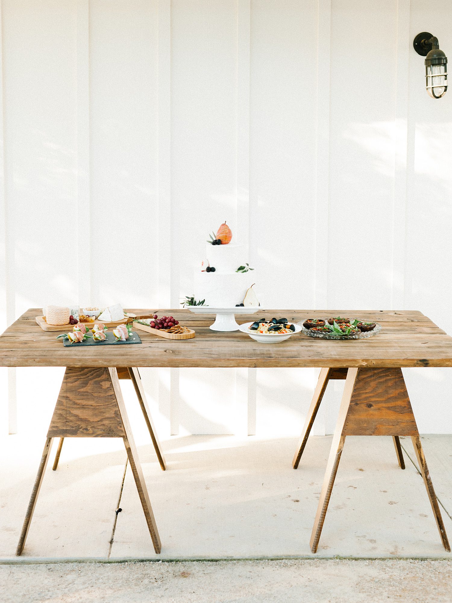 Food on rustic table in front of border and baton white siding at Biddle Ranch Vineyard Wedding by Edna Valley Wedding Photographer Austyn Elizabeth Photography