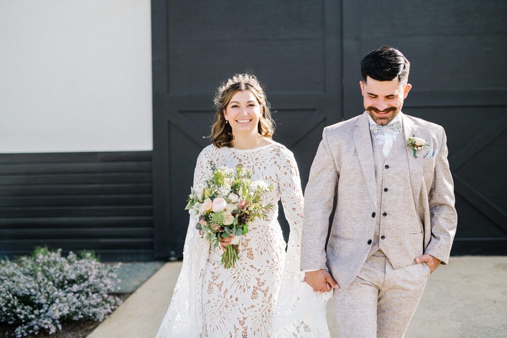Bride and groom walk in front of black barn door at La Lomita Ranch Wedding by Bohemian Wedding Photographer Austyn Elizabeth Photography