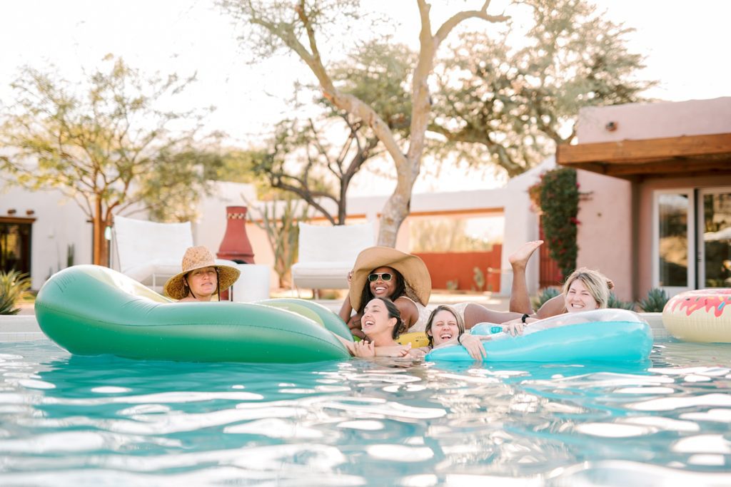 Six wedding photographers swimming in a pool at Villa Leche Palm Desert Airbnb by San Luis Obispo Wedding Photographer Austyn Elizabeth Photography