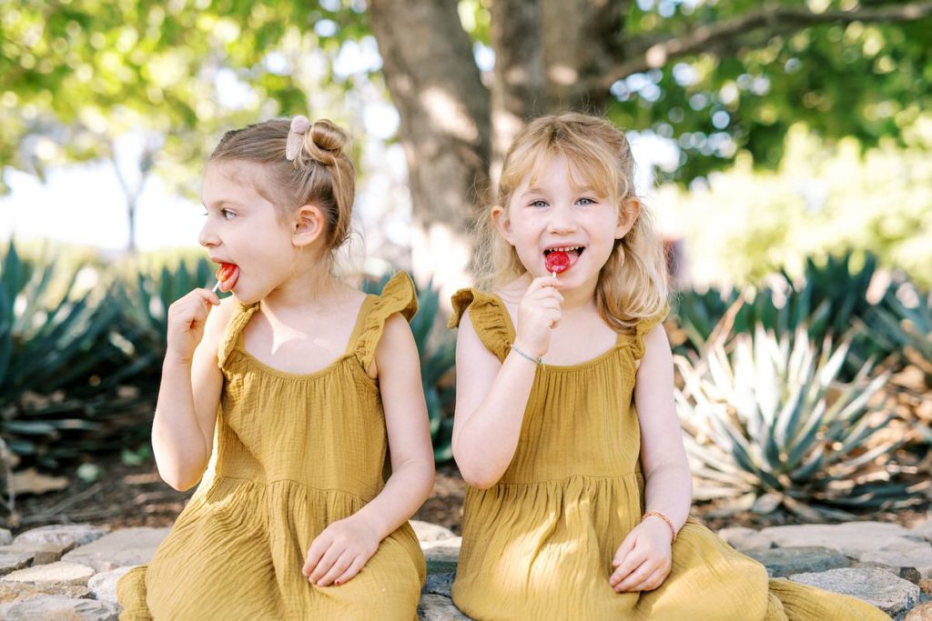 Girls in mustard linen dresses lick lolly pops at MarFarm by San Luis Obispo Family Photographer Austyn Elizabeth Photography