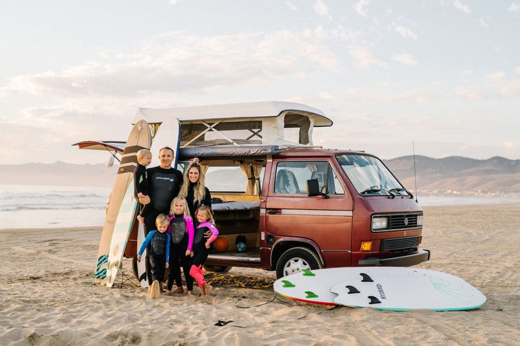 Family playing in the sand in wetsuits with westy and surfboards on Pismo Beach by San Luis Obispo family photographer Austyn Elizabeth Photography