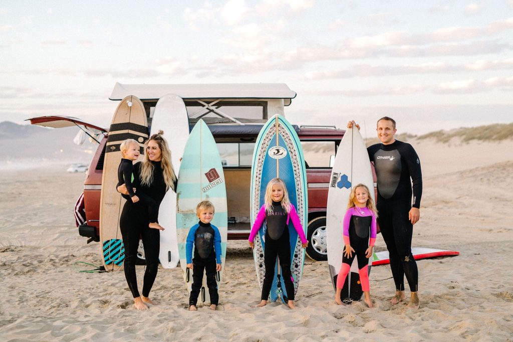 young family in wetsuits at Pismo beach with surfboards and a VW Westy at sunset by Central Coast Family photographer Austyn Elizabeth Photography