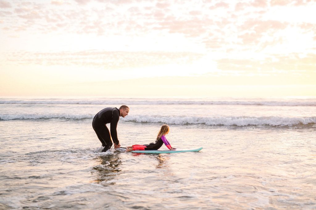 Dad teaching young daughter how to surf during pismo beach family session with VW Westy by Pismo Beach Photographer Austyn Elizabeth Photography