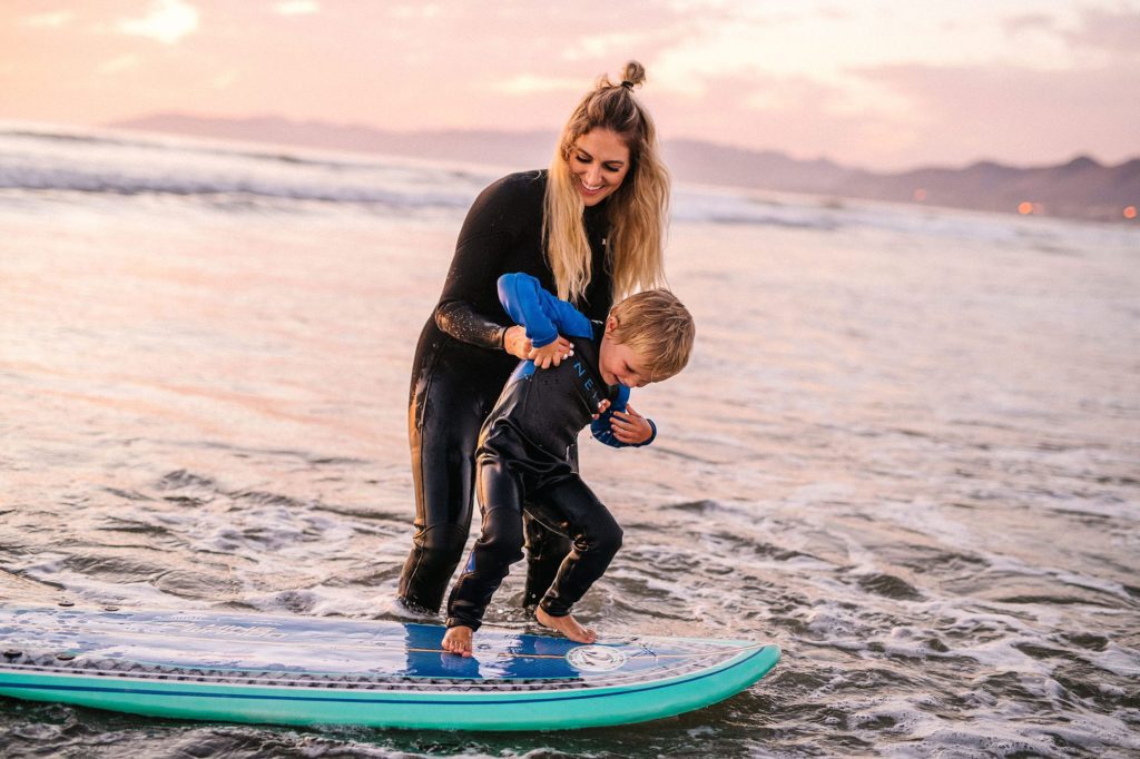 Mom teaching balance on surfboard on Pismo beach by SLO family photographer Austyn Elizabeth Photography