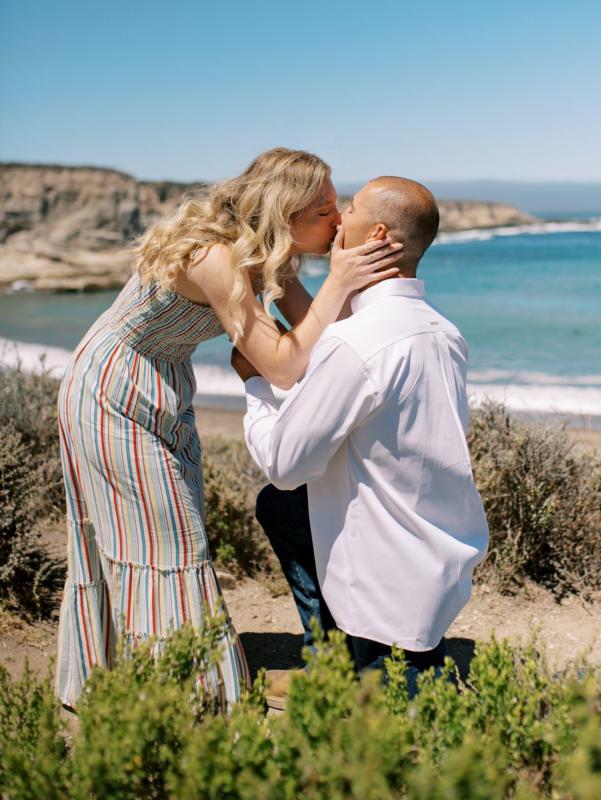 Kisses and yes at surprise proposal at Montana De Oro's Spooners Cove by Pismo beach engagement photographer austyn elizabeth photography