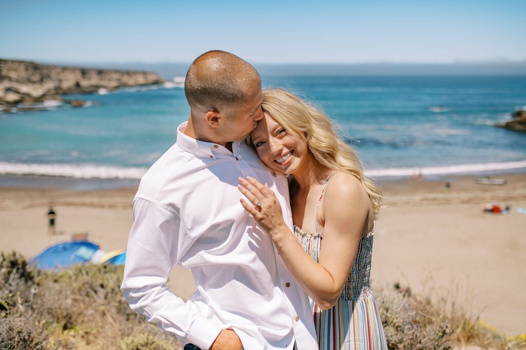 Bride holds onto groom at surprise proposal at Montana De Oro's Spooners Cove by Pismo beach engagement photographer austyn elizabeth photography