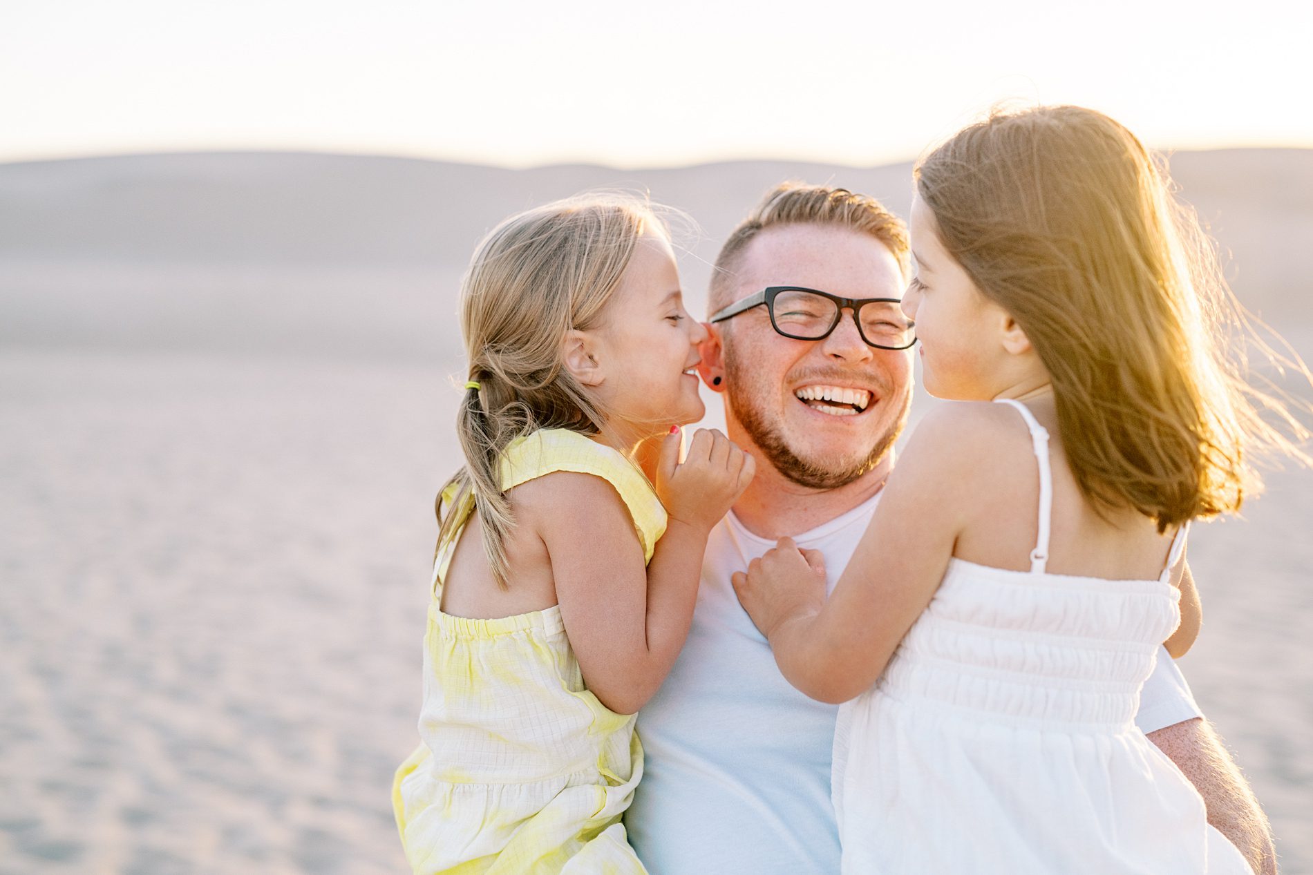 Daughter whispers in dad's ear and dad laughing so hard at the Oceano Dunes in Pismo Beach by Pismo Beach Family Photographer Austyn Elizabeth Photography
