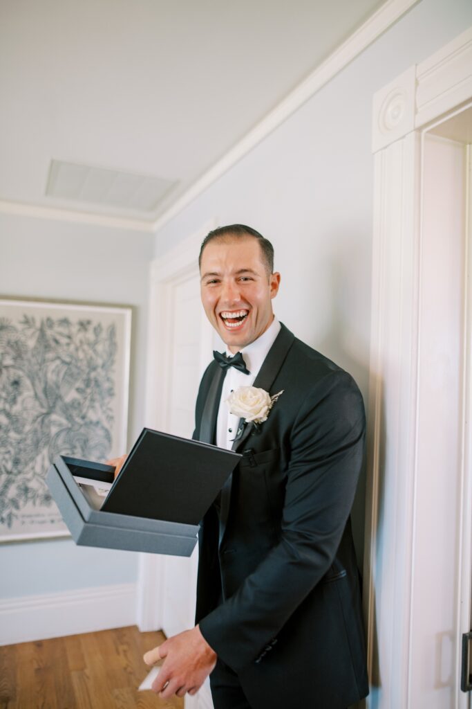Groom laughs after receiving surprise black book from bride before wedding ceremony at Lamoure Vineyard wedding at Le Reve Estate by Pismo Beach wedding photographer Austyn Elizabeth Photography