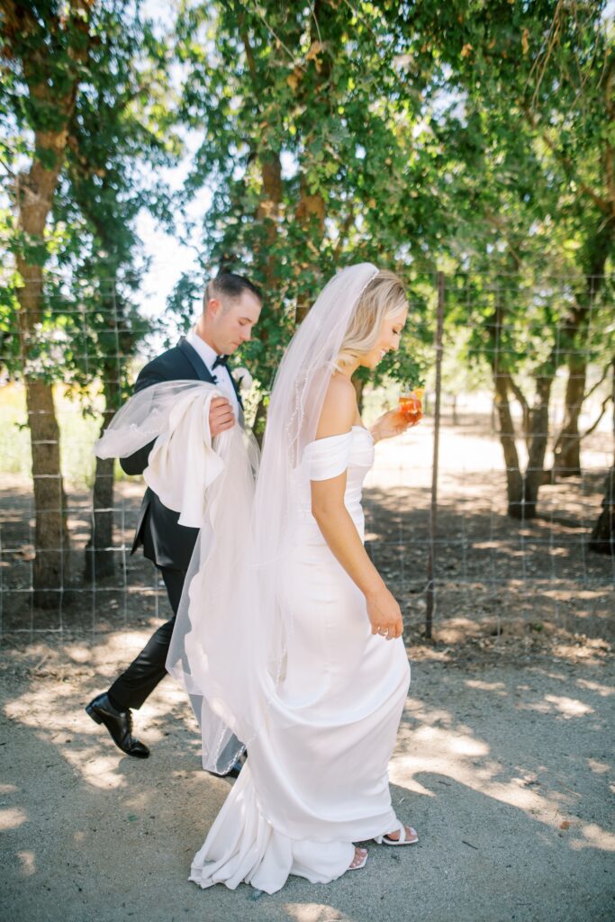 Groom holds bride's dress at Lamoure Vineyard wedding by Pismo Beach wedding photographer Austyn Elizabeth Photography