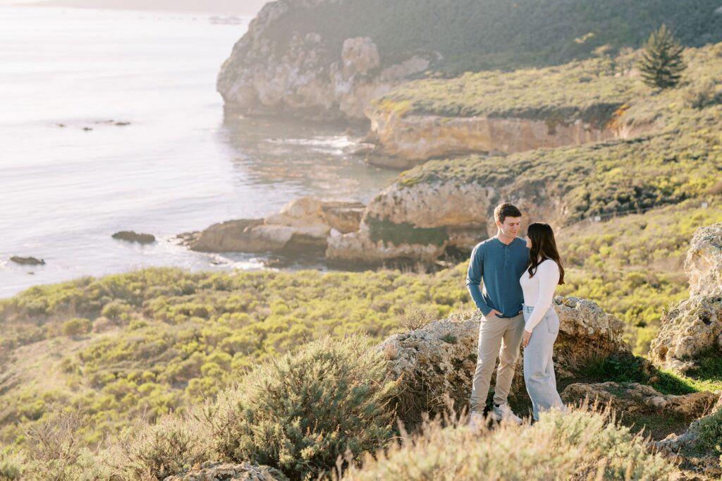 Guy and Girl standing with Pismo beach's rugged cliff cloastline in the background at Pirates Cove at Pismo Beach Engagement session by Pismo Beach Wedding Photographer Austyn Elizabeth Photography