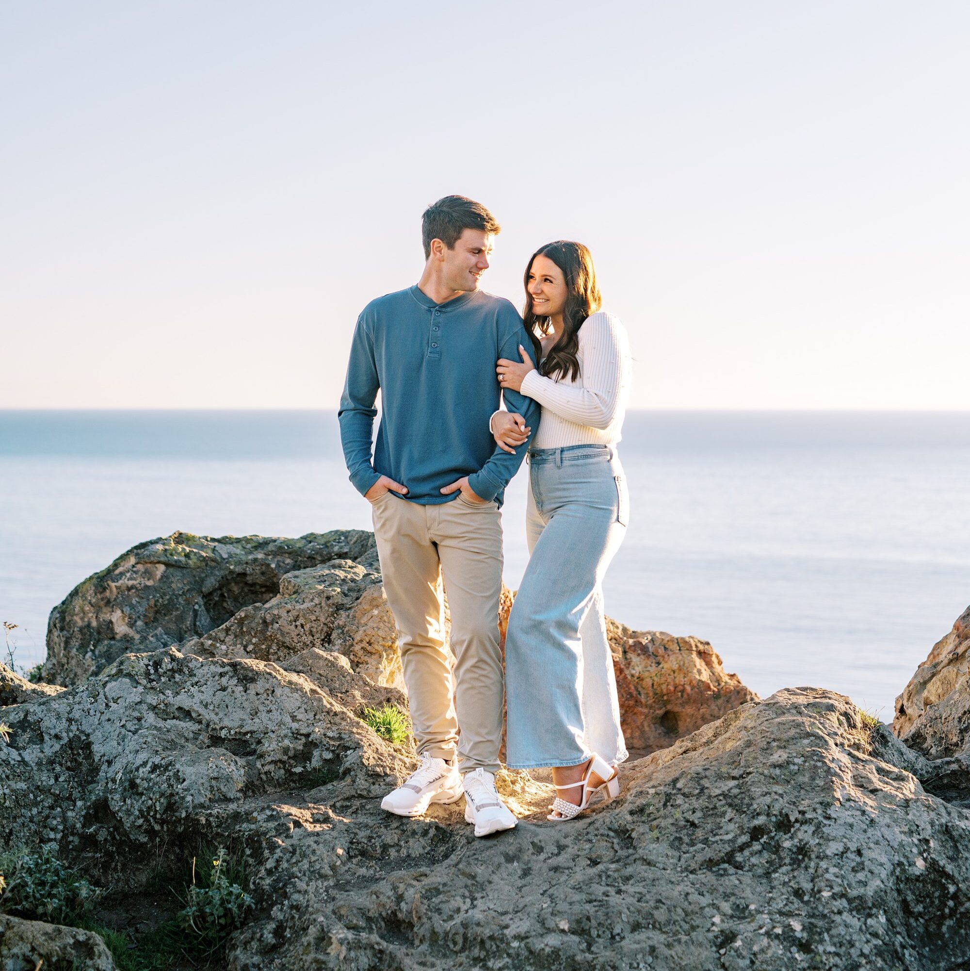 Couple stand on Pirates Cove rock with pacific ocean in background at Central Coast Engagement session by Pismo Beach Engagement Photographer Austyn Elizabeth Photography
