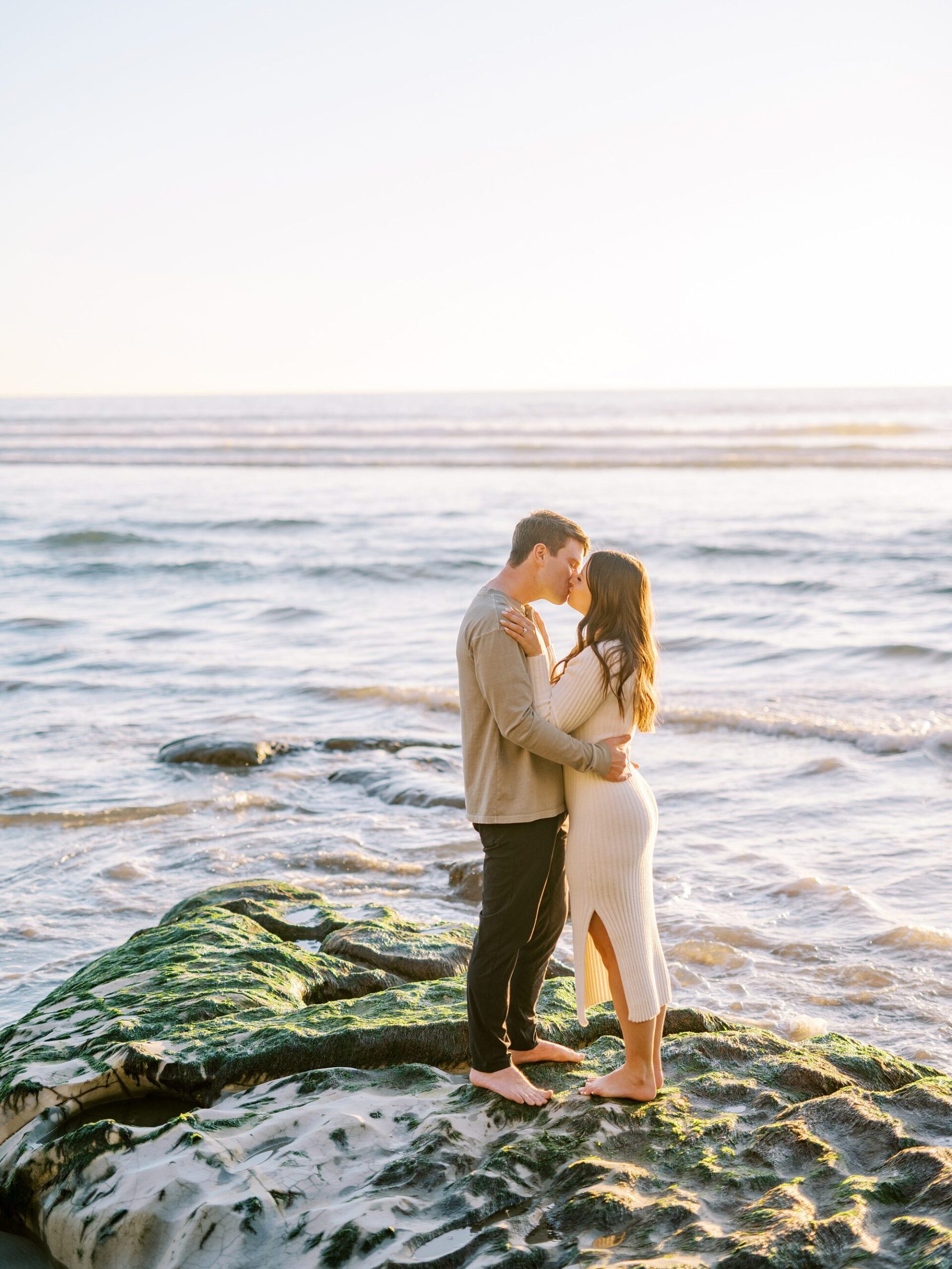 Couple sand on rock in the middle of ocean at Pismo Beach Engagement session by Pismo Beach Engagement Photographer Austyn Elizabeth Photography