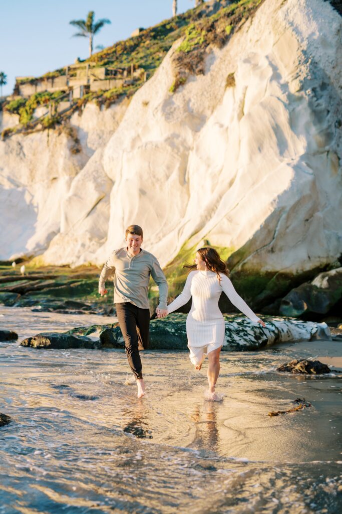 Couple run in the water at Pismo Beach Engagement session by Pismo Beach Engagement Photographer Austyn Elizabeth Photography
