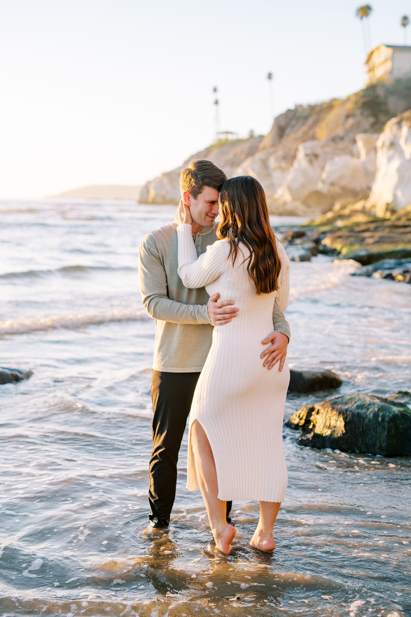 Couple embrace each other  while standing on water at Pismo Beach Engagement session by Pismo Beach Wedding Photographer Austyn Elizabeth Photography