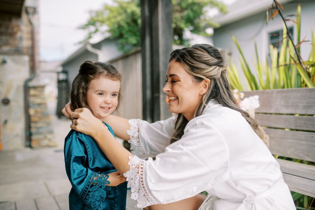 Bride putting neckless on her flower girl by Cayucos Wedding Photographer on Film by Austyn Elizabeth Photography