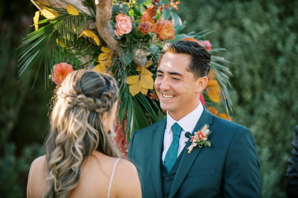 Groom smiles at his bride during tropical wedding ceremony by Cayucos Wedding Photographer on Film by Austyn Elizabeth Photography