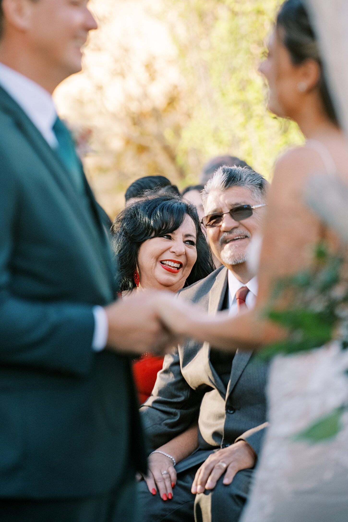 Groom's parents hold hands and laugh at each other during wedding ceremony by Cayucos Wedding Photographer on Film by Austyn Elizabeth Photography