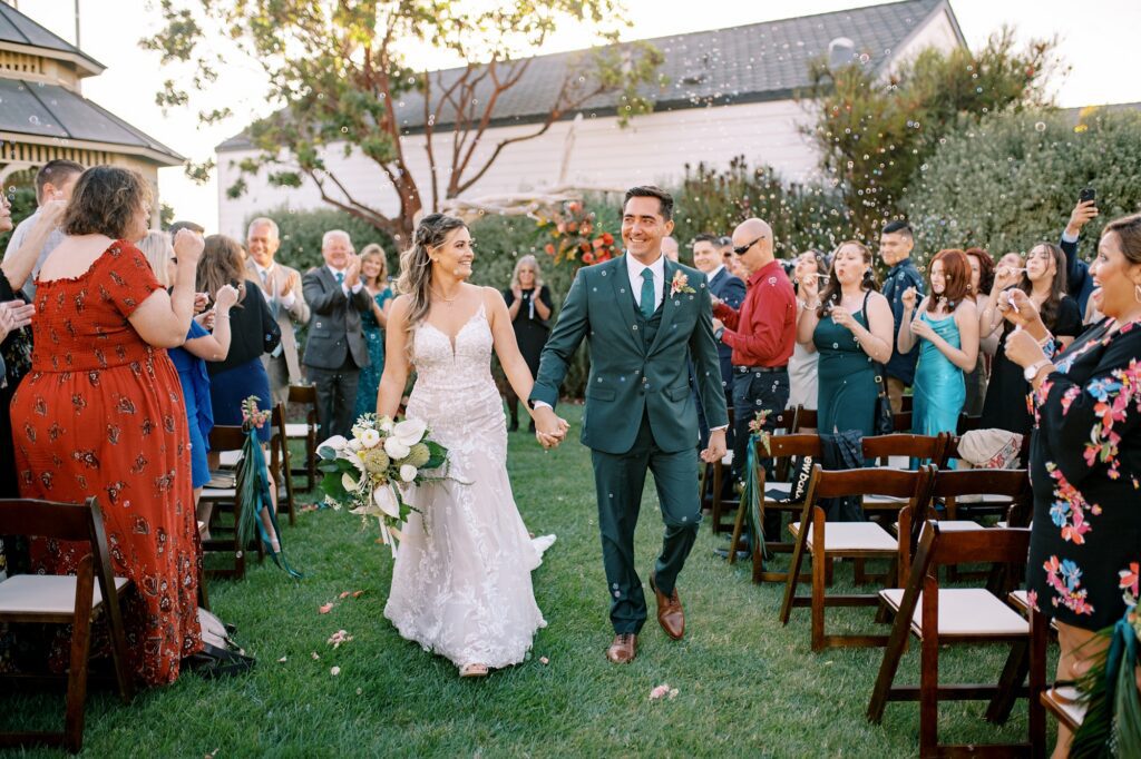 Couple walks down aisle with guests blowing bubbles by Cayucos Wedding Photographer on Film by Austyn Elizabeth Photography