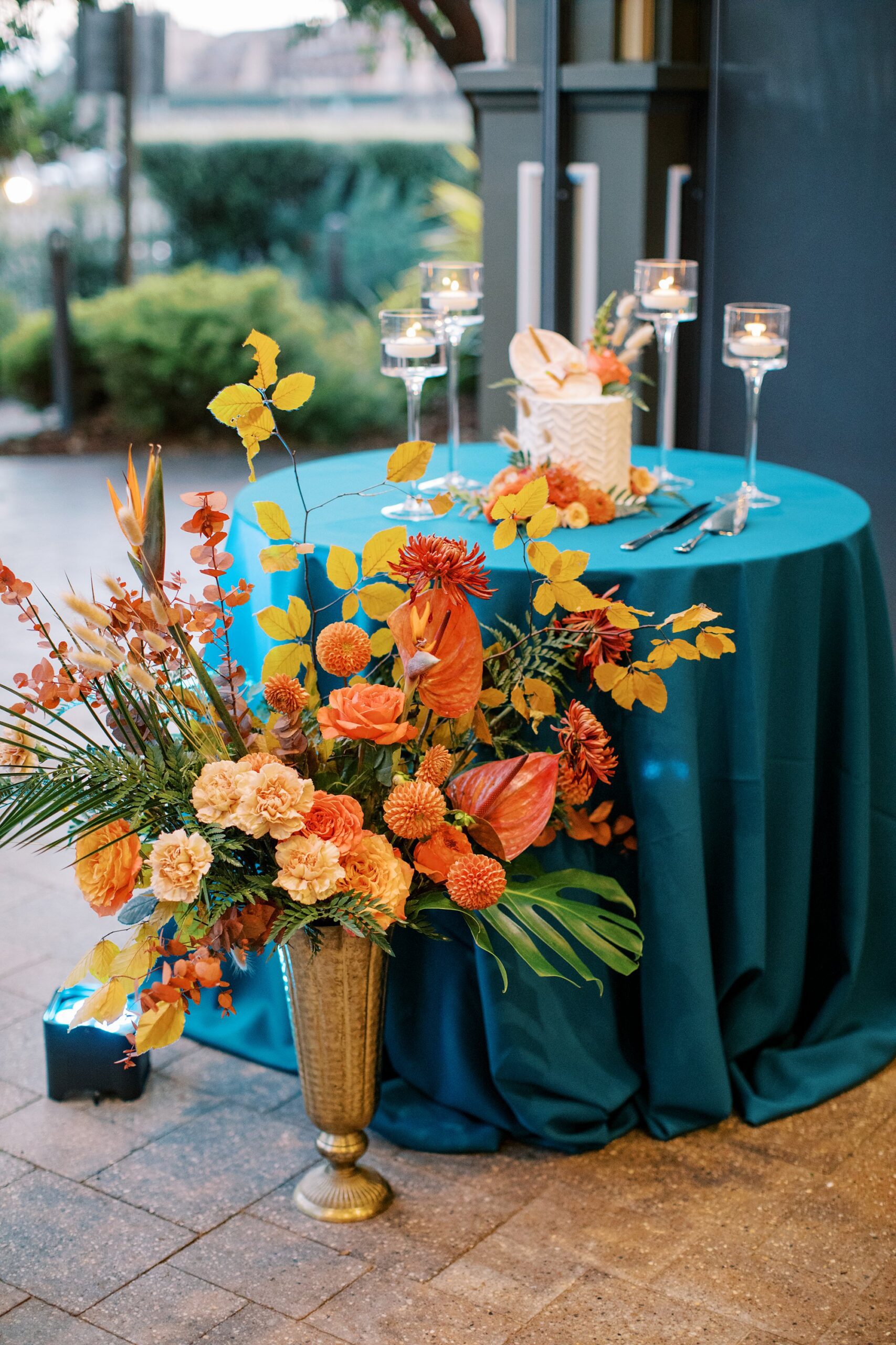 Teal linens and gold pink red and peach tropical flowers in front of cake cutting table by Cayucos Wedding Photographer on Film by Austyn Elizabeth Photography