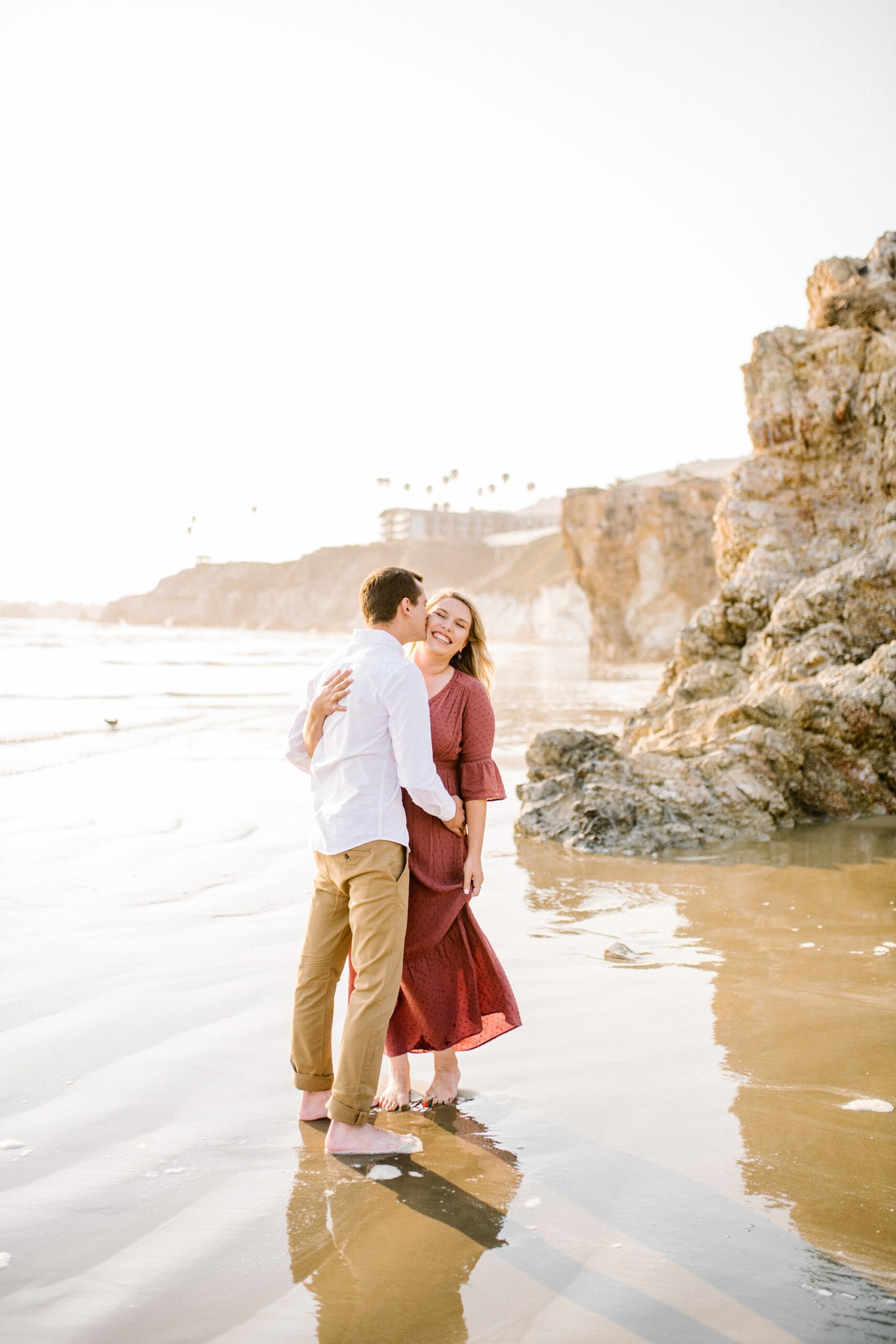 Groom kisses his bride on the beach by Pismo Beach Engagement Photographer Austyn Elizabeth Photography