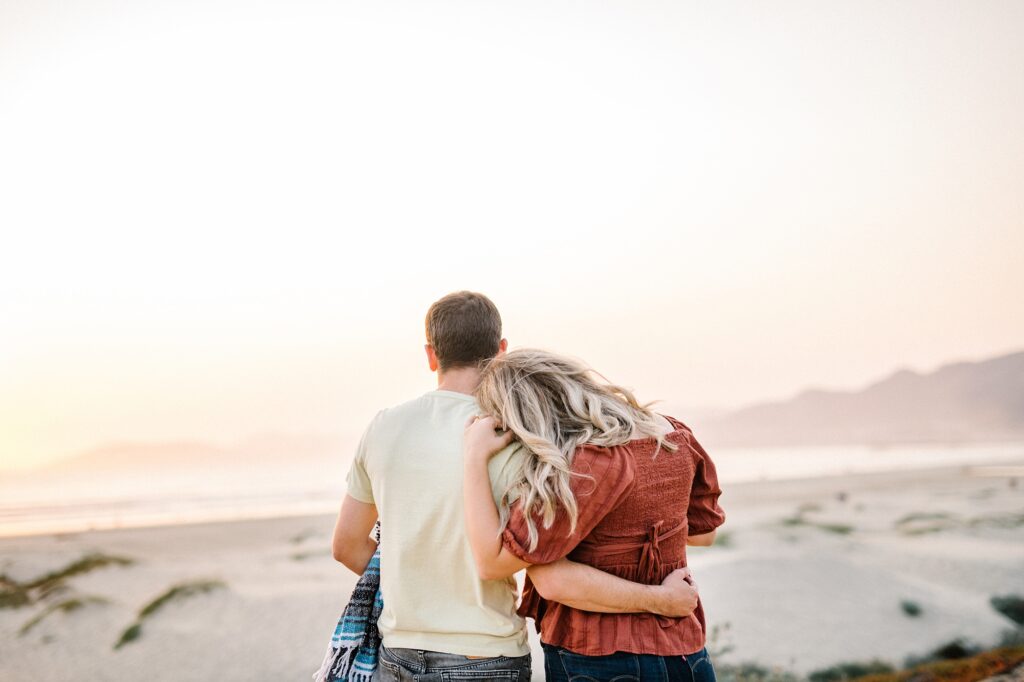 Couple watch the sunset during engagement session by Pismo Beach Engagement Photographer Austyn Elizabeth Photography