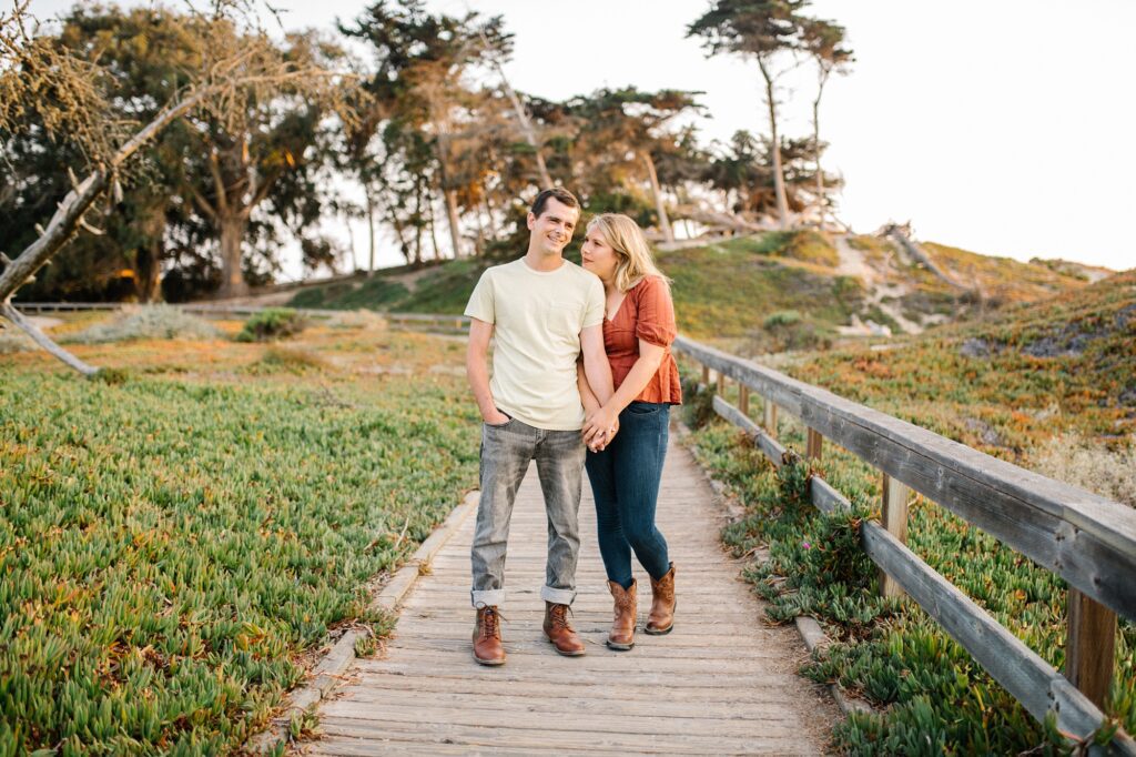 Couple stand on board walk by Pismo Beach Engagement Photographer Austyn Elizabeth Photography