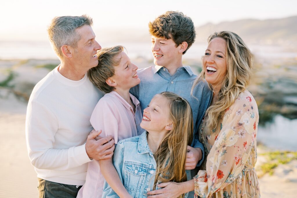 Family laughs together with pismo beach hills in the distance by Pismo Beach Family Photographer Austyn Elizabeth Photography