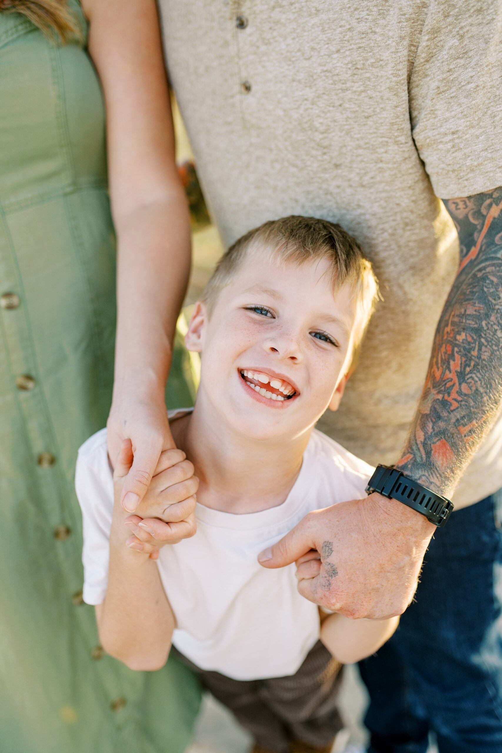 Close up photo of an 8 year old holding onto his dad's hands and smiling at the camera during Morro Bay Family Photos by Morro Rock Family Photographer Austyn Elizabeth Photography