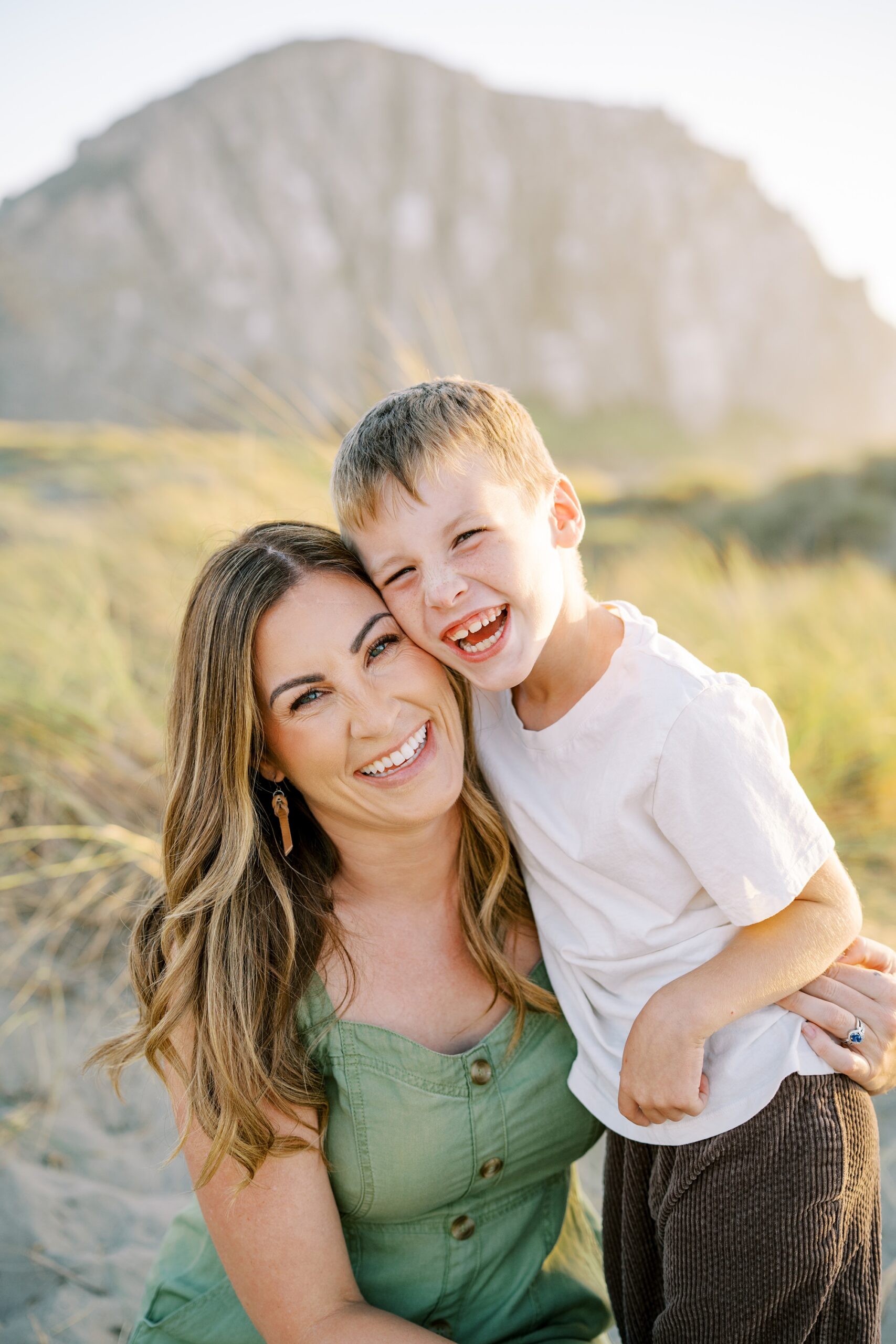 eight year old laughing while hugging his gorgeous mama during their golden hour morro bay family photos by Morro Bay Family Photographer Austyn Elizabeth Photography