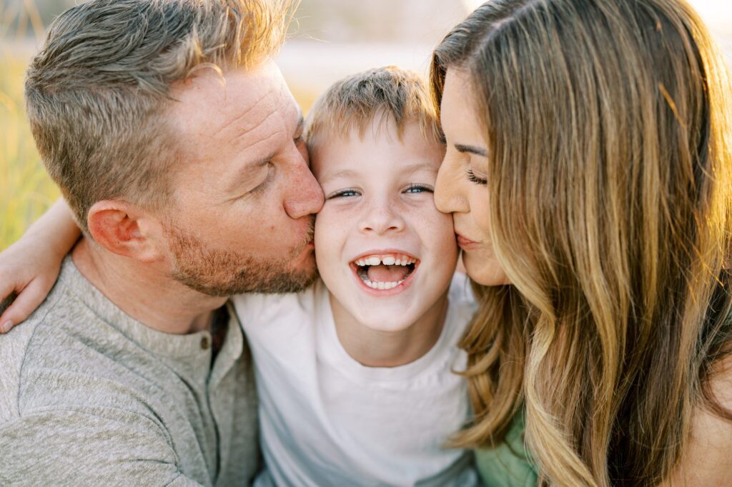 Mom and dad kiss eight year old's face during family photos by Morro Bay Family Photographer Austyn Elizabeth Photography