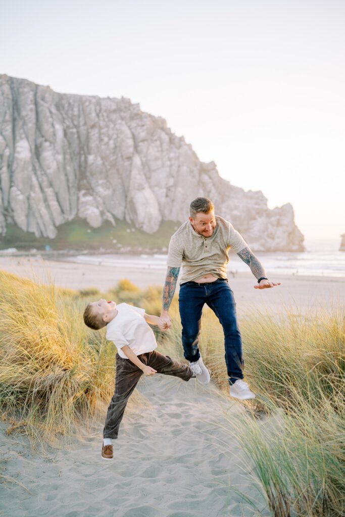 Dad and son jump in front of morro rock by Morro Bay Family Photographer Austyn Elizabeth Photography